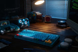 8BitDo Ultimate 2 Wireless 2.4G – Controller – Clear Blue – controller og blåt tastatur på skrivebord; producentillustration
